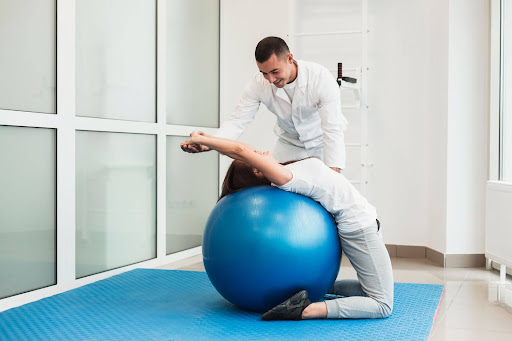Doctor stretching a patient on a gym ball